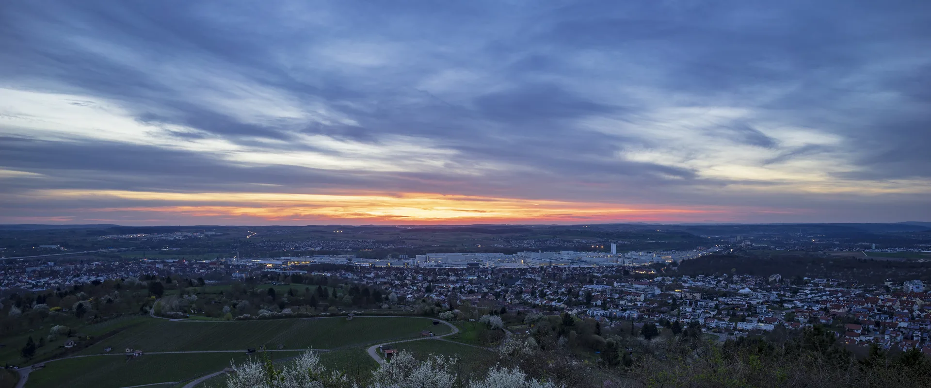 Blick vom Scheuerberg über Neckarsulm im Abendrot, im Hintergrund die Werksanlagen im Norden der Stadt